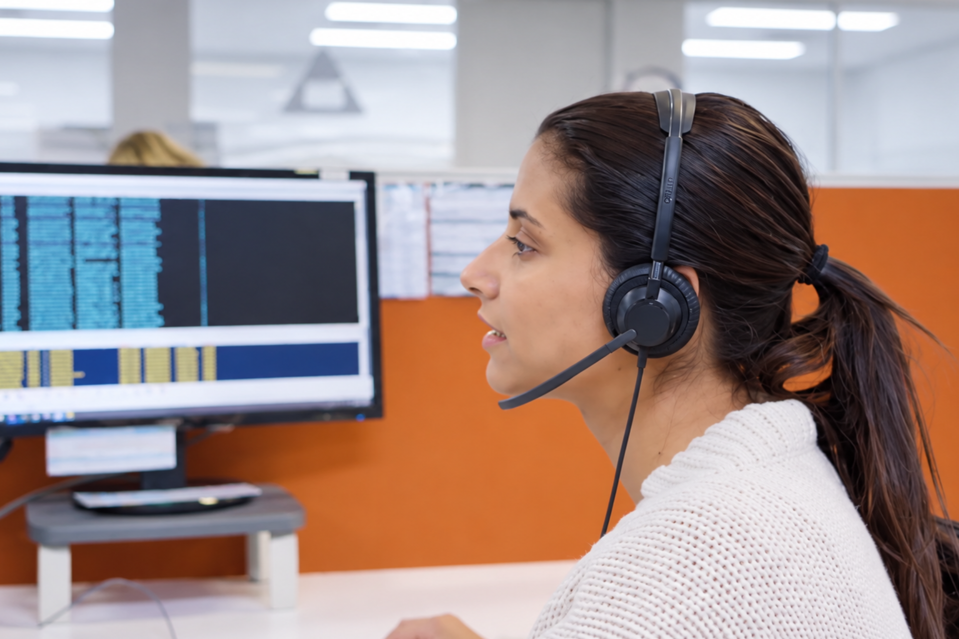 INS nurse wearing a headset at a desk, looking at a computer monitor