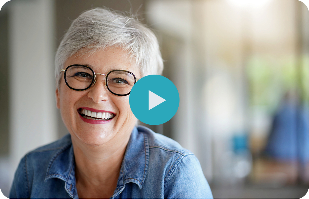 A woman is smiling while sitting on a couch in front of a play button.