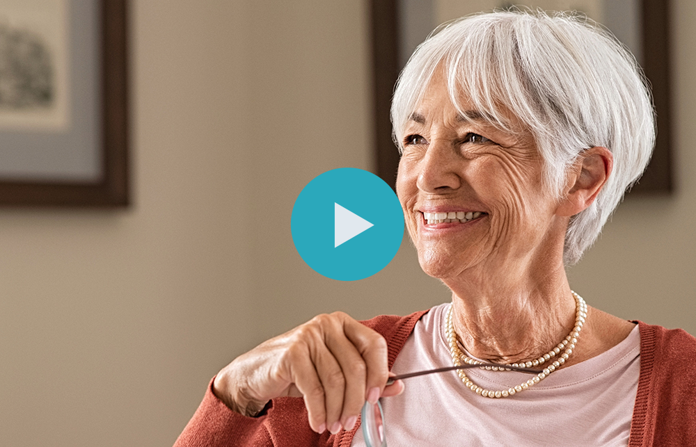 Smiling woman with short white hair holding eyeglasses