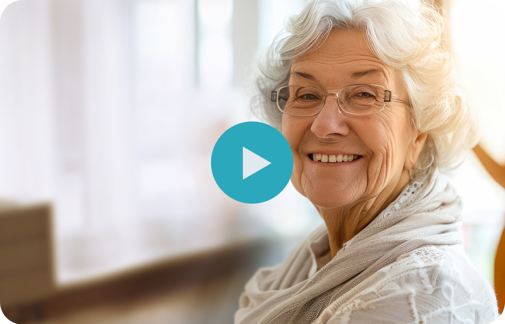 An elderly woman wearing glasses and a scarf is smiling.