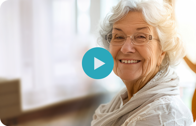 An elderly woman wearing glasses and a scarf is smiling.