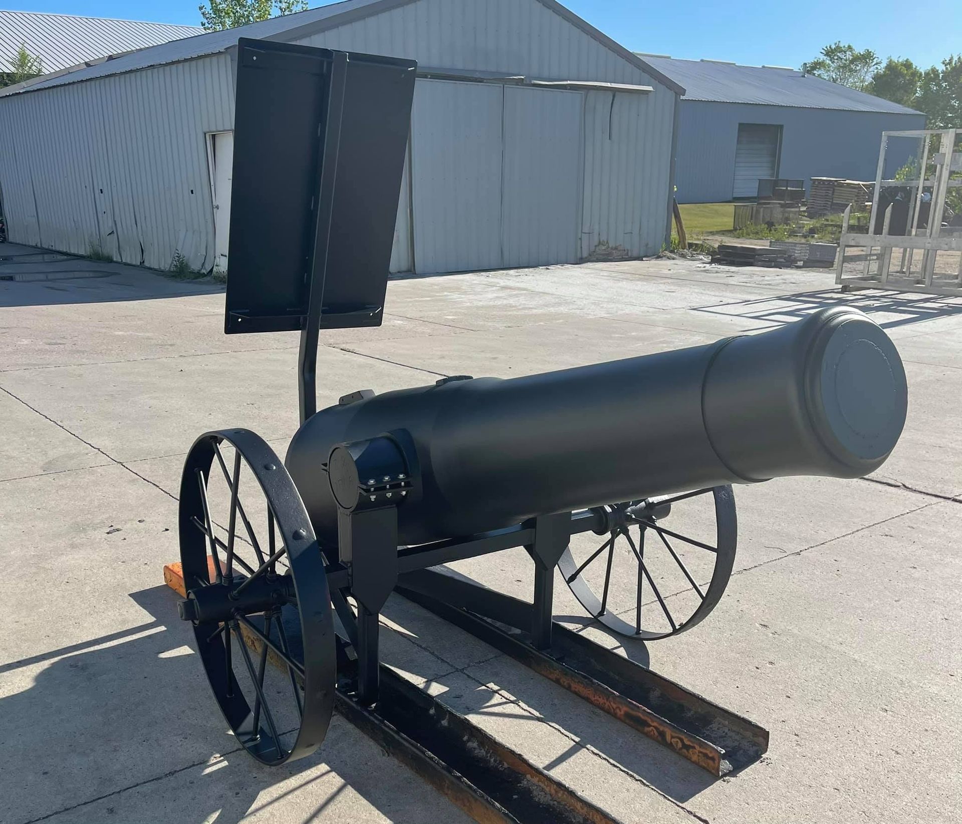 a large black cannon with wheels sits in a parking lot