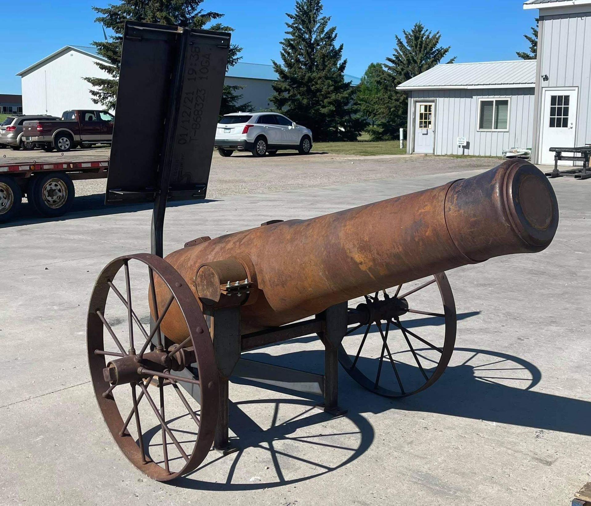 a rusty cannon sits in front of a white building