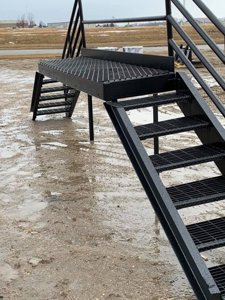 a set of metal stairs sitting on top of a muddy field