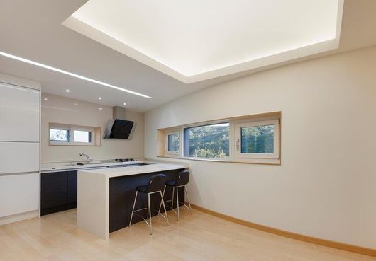 Bright modern kitchen with white cabinets, island seating, and large windows.