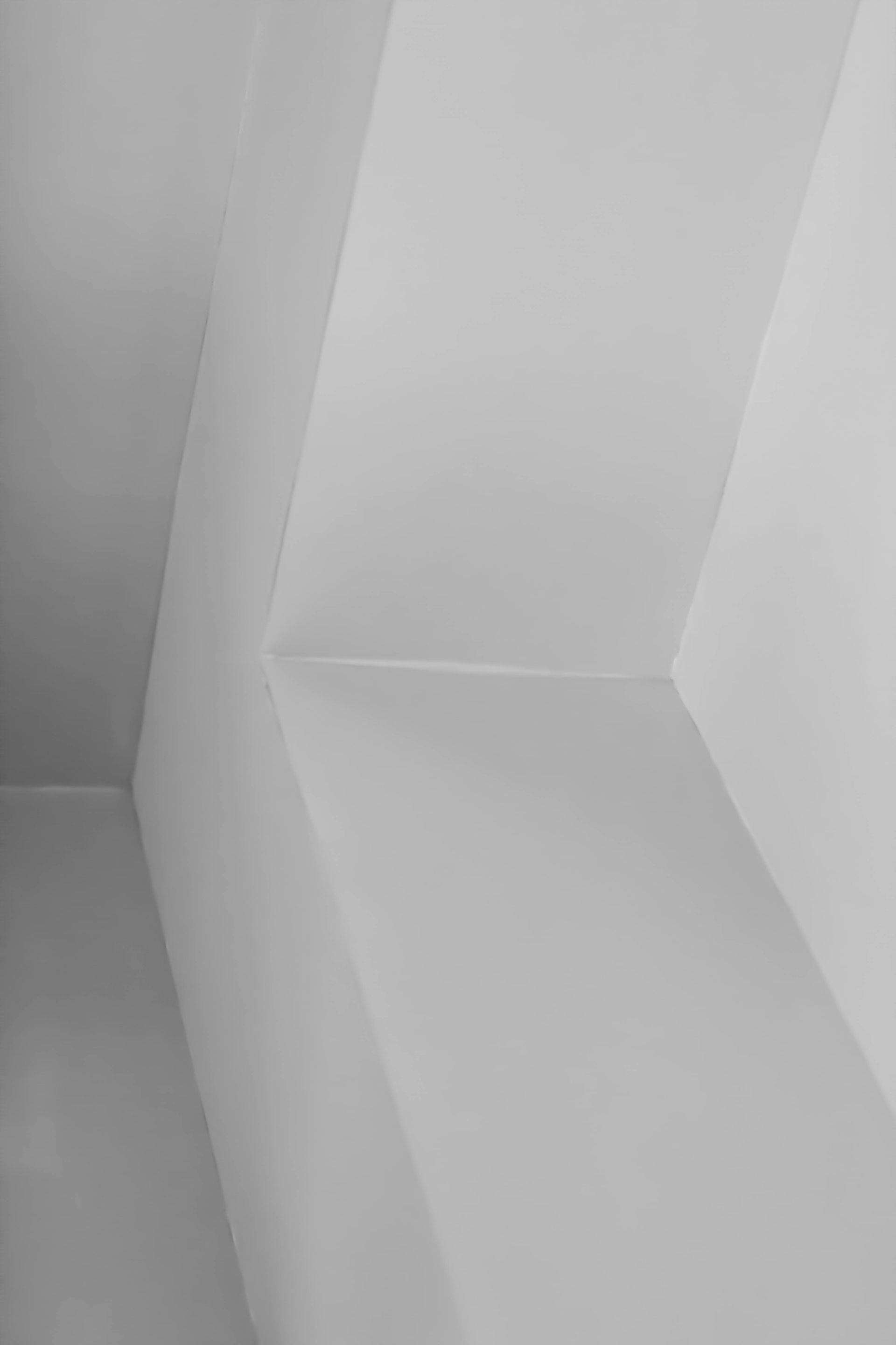 White geometric ceiling corner with angular wall panels and soft shadows
