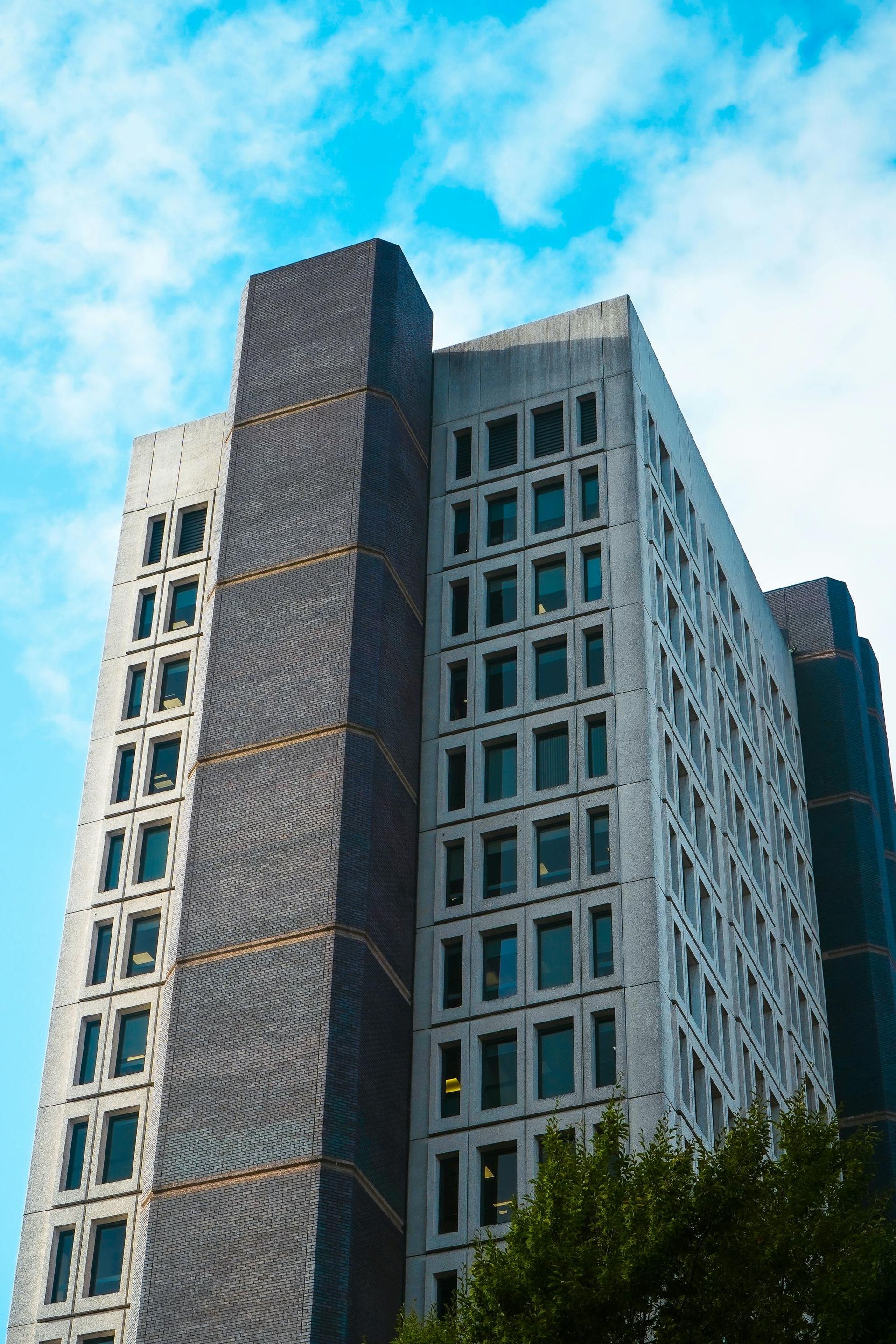 Tall modern office building with white and dark gray facade against a blue sky