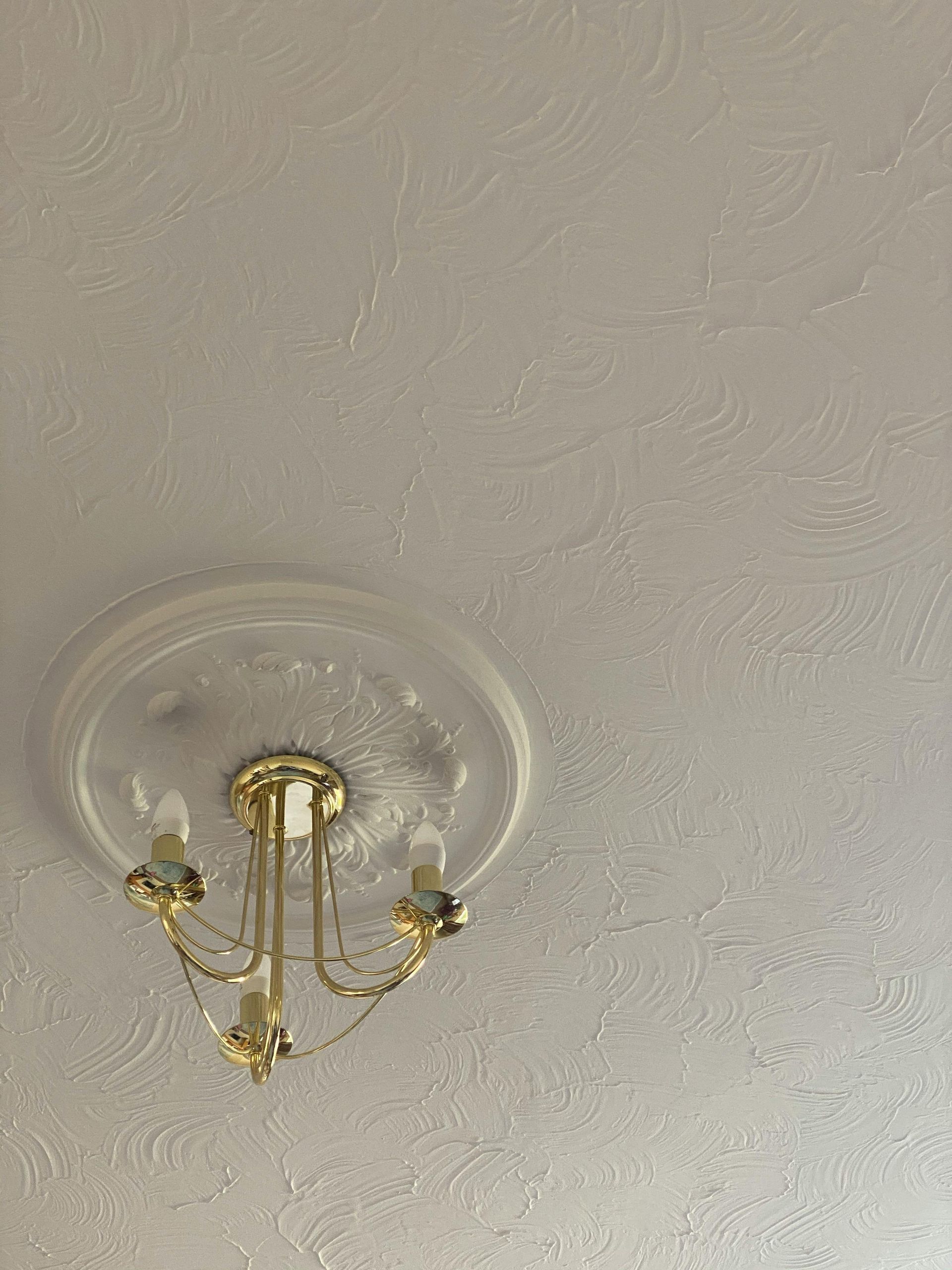 Gold ceiling light fixture on a textured white ceiling.