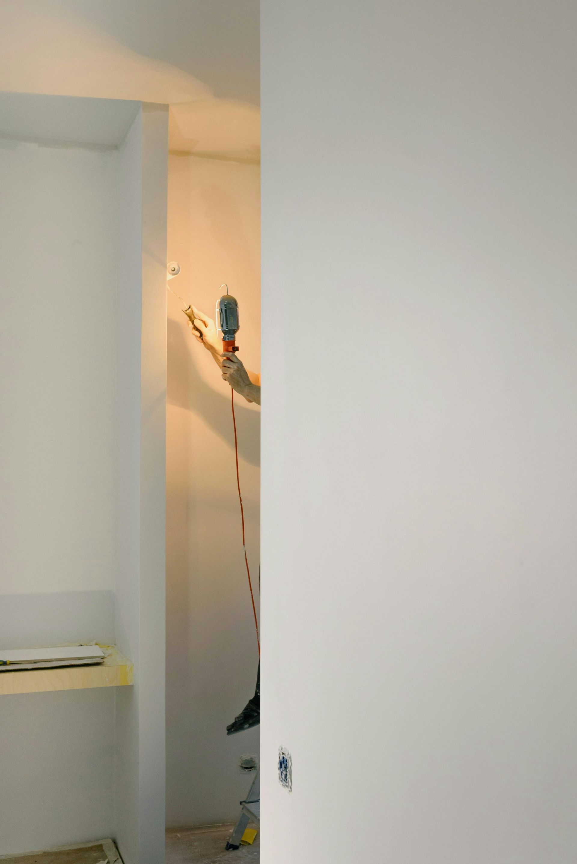 Partially open doorway with a hanging bird decoration and a small shelf in a plain room