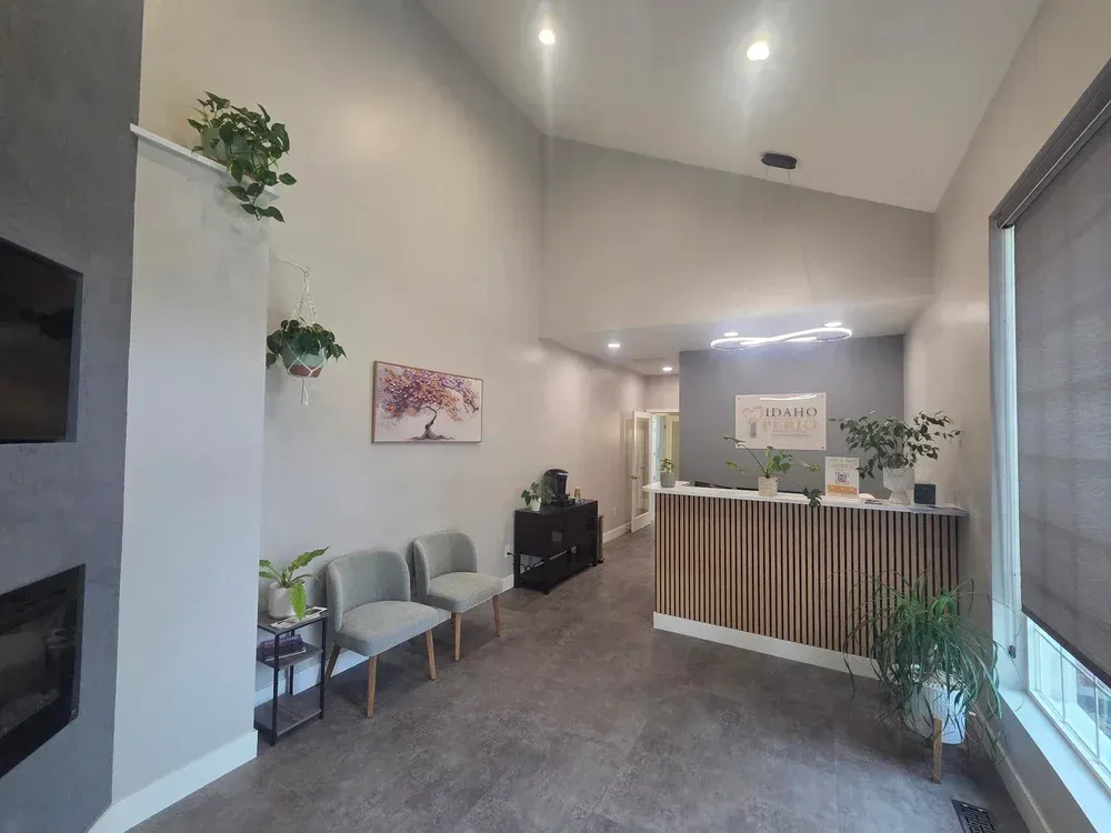 Modern office lobby with reception desk, gray seating, potted plants, and carpeted floor