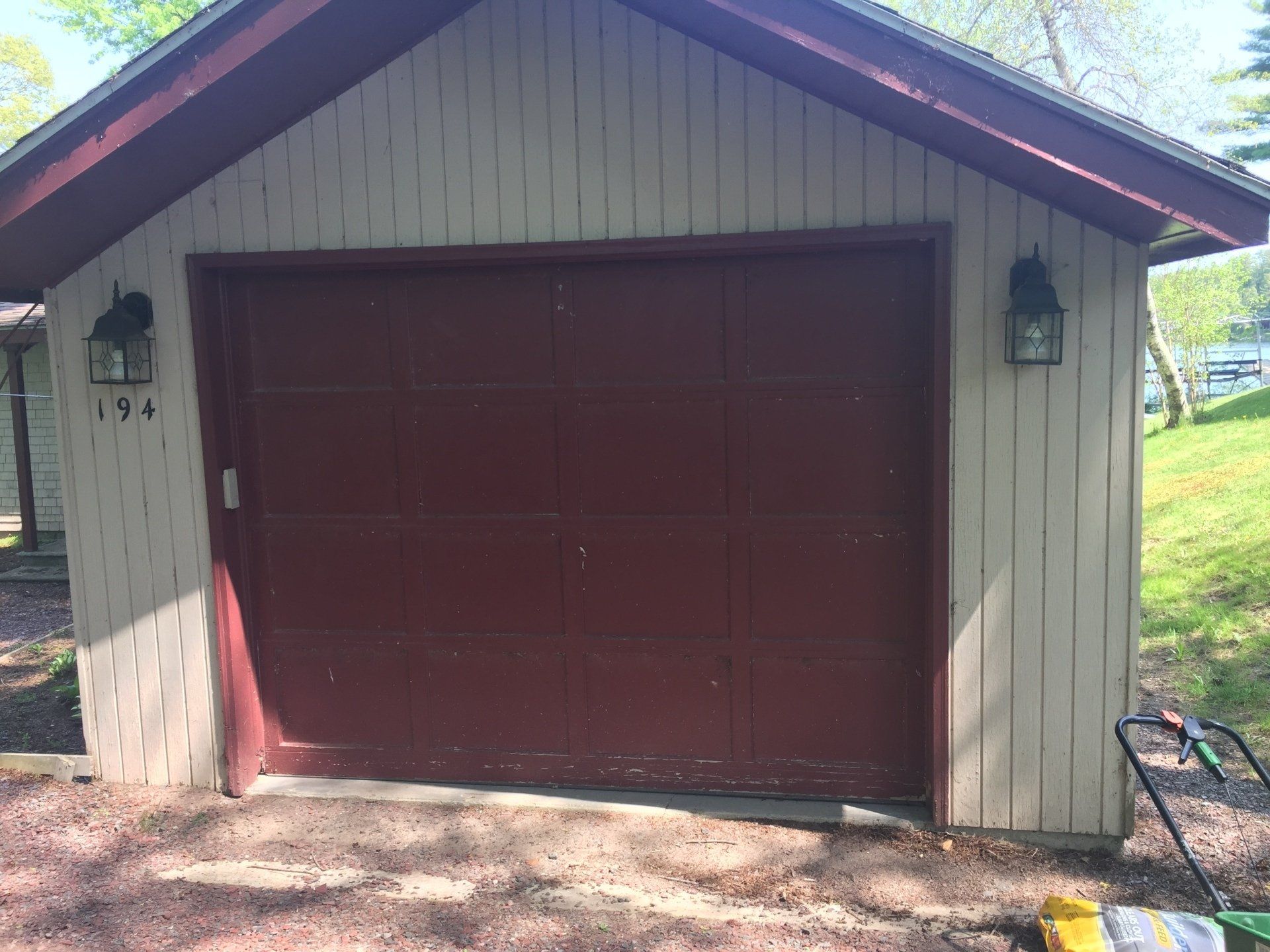 Red garage door on a beige garage with a brown trim and two black lights.