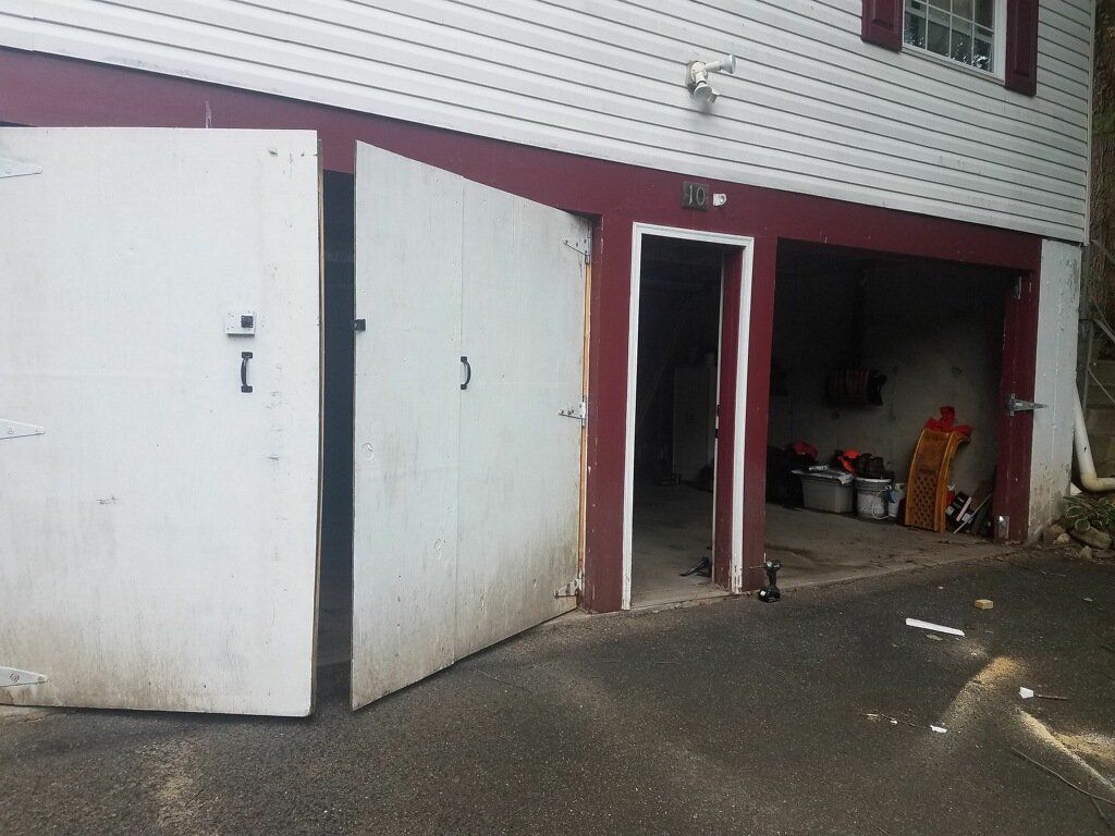 White garage doors, partially open. Red trim surrounds the doors and entrance. Exterior of a building.