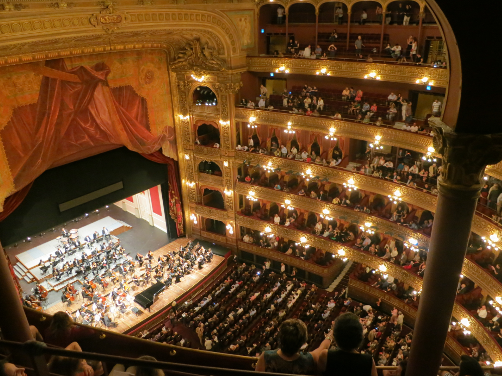 A large auditorium filled with people watching an orchestra perform