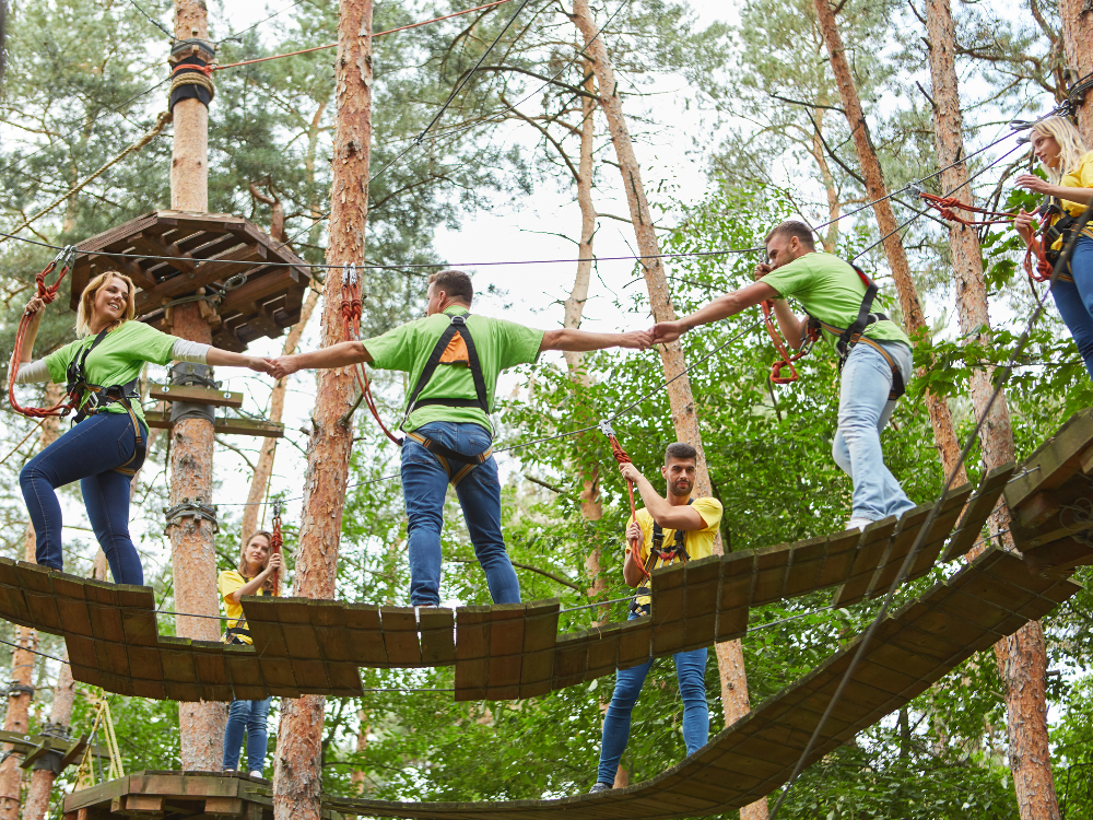 A group of people are standing on a wooden bridge holding hands.