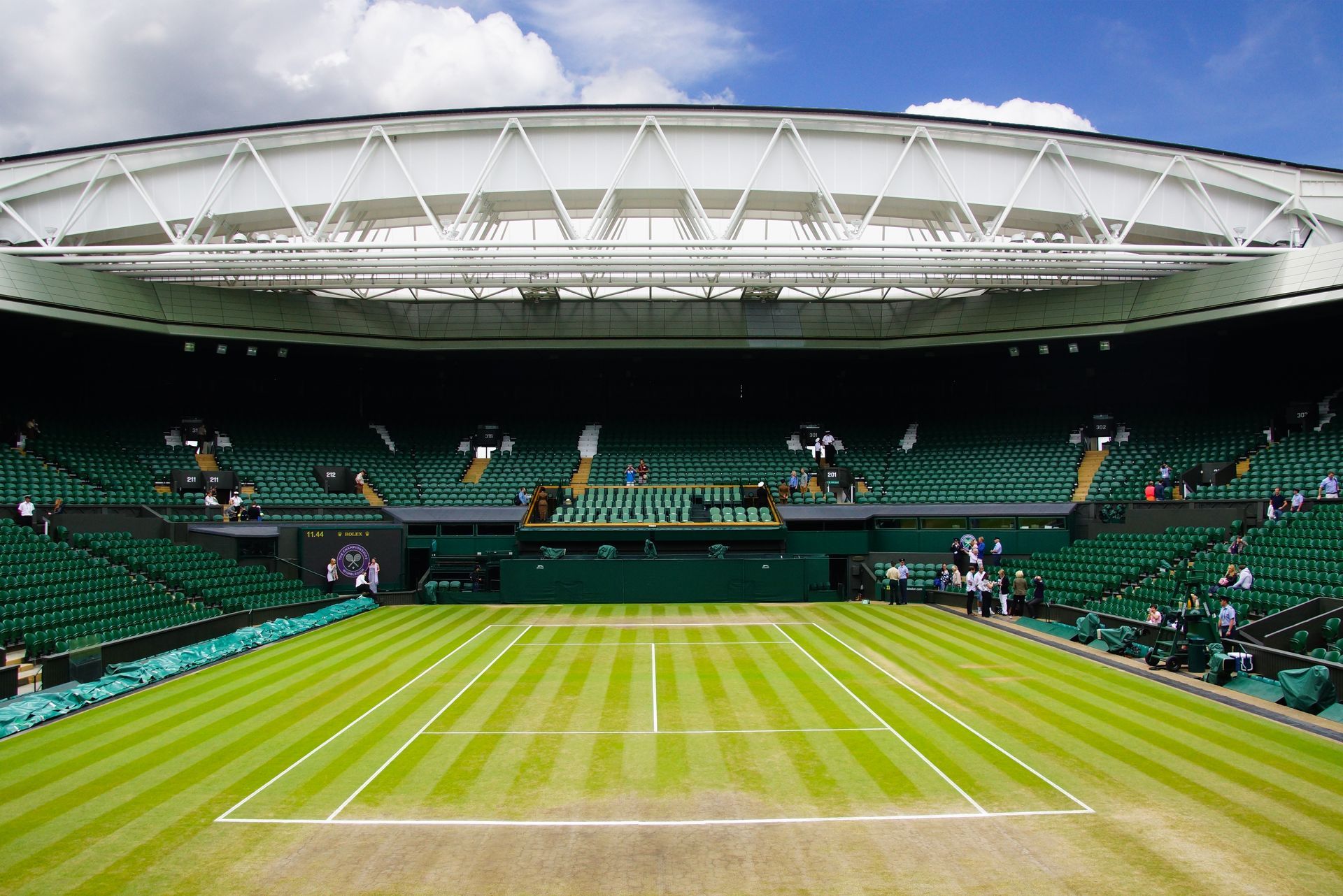 An empty tennis court with a stadium in the background