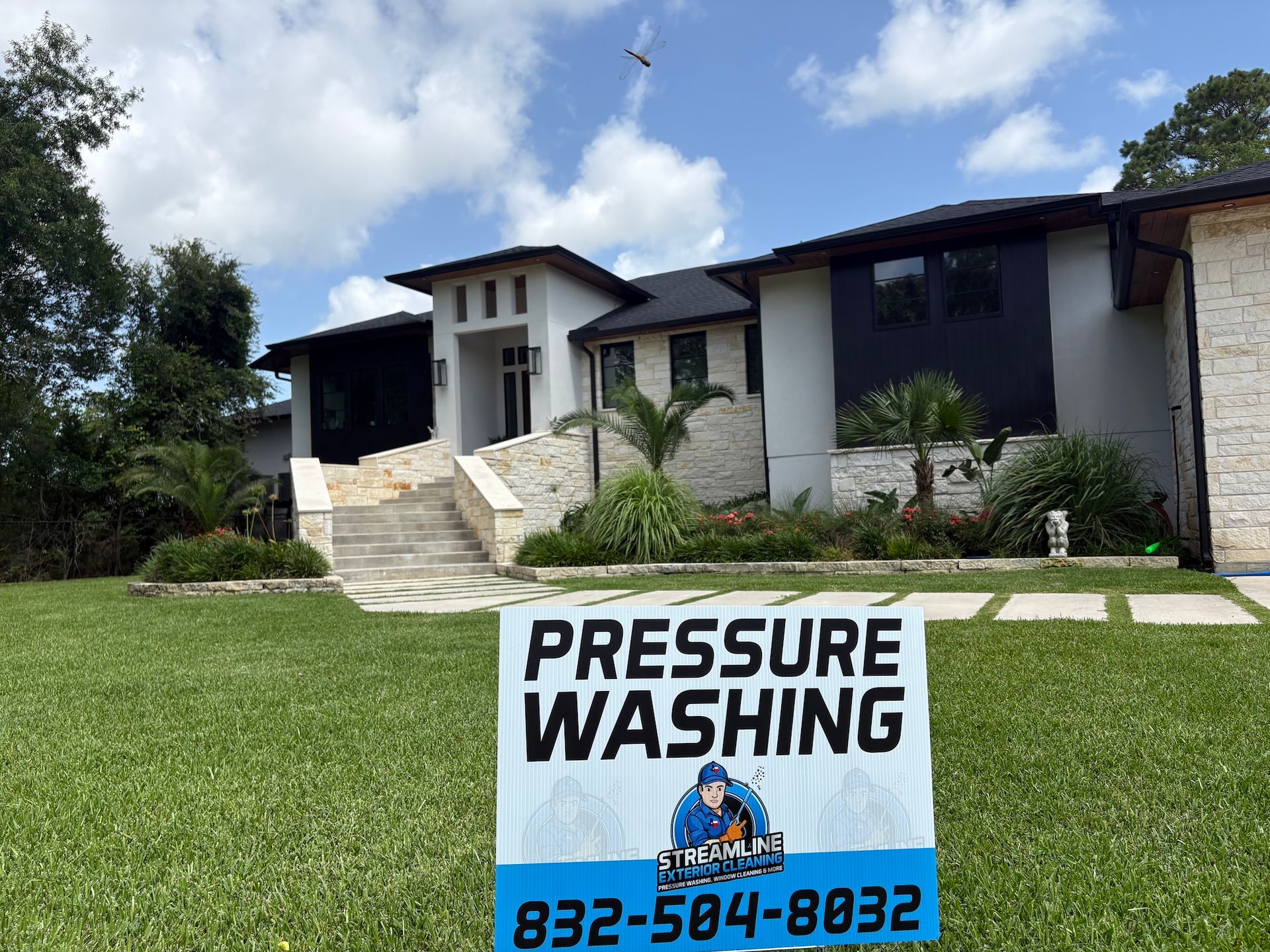Pressure washing service sign on a lawn in front of a modern house