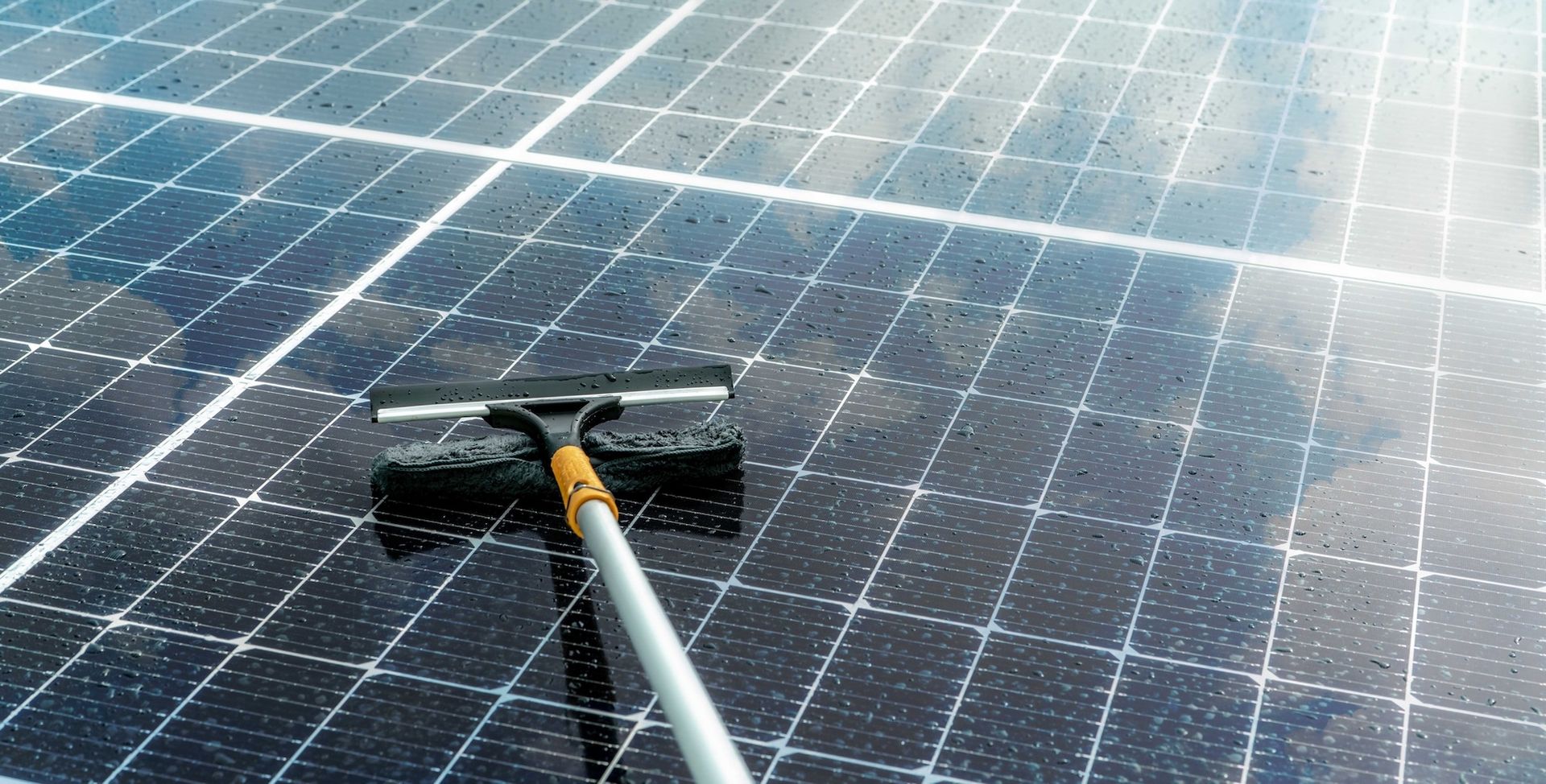 Squeegee cleaning blue solar panels with water spray