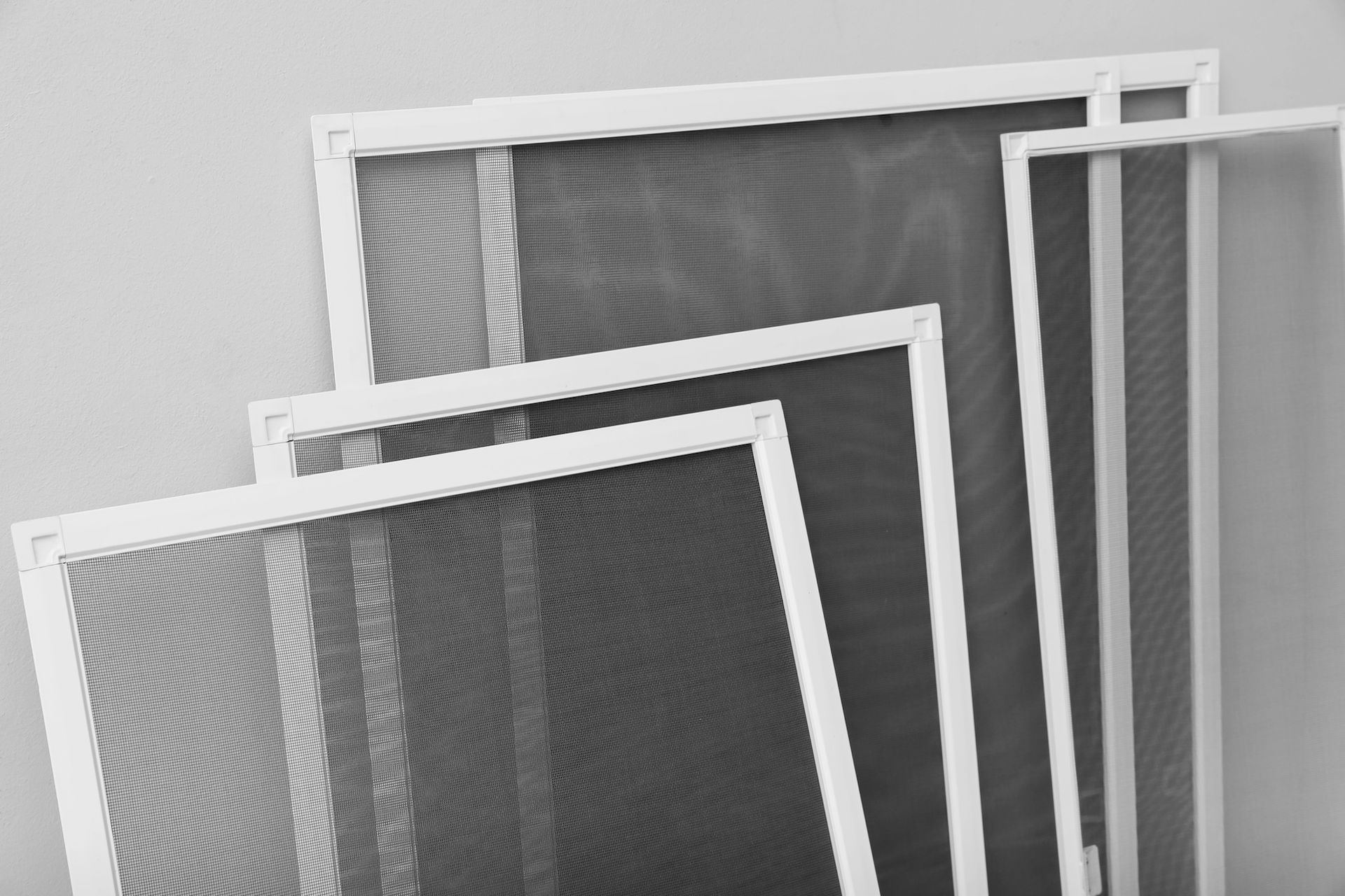 Stacked white-framed screens or mesh panels in grayscale, overlapping against a light background