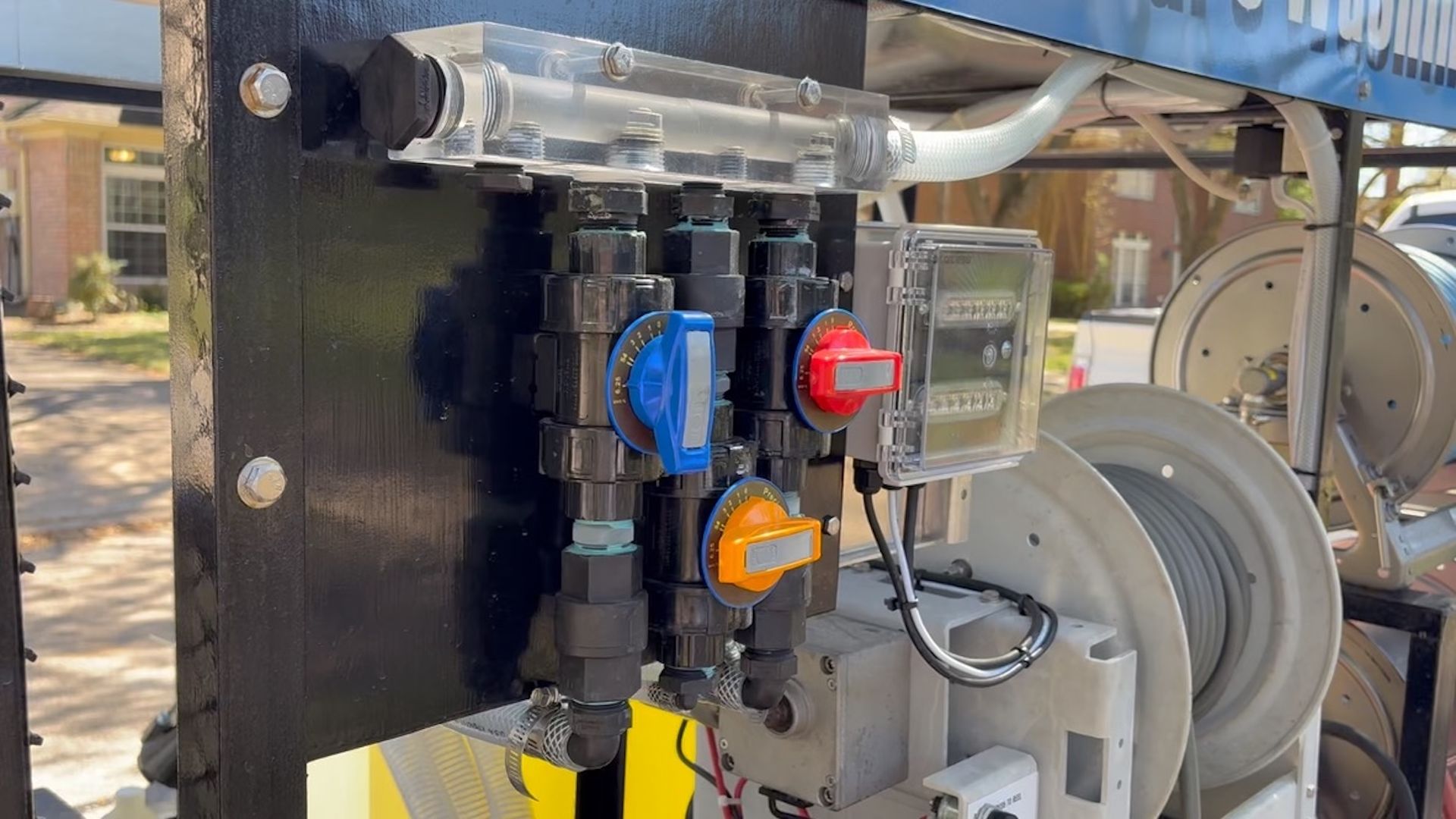 Control panel with red, blue, and orange buttons mounted on industrial machinery outdoors.