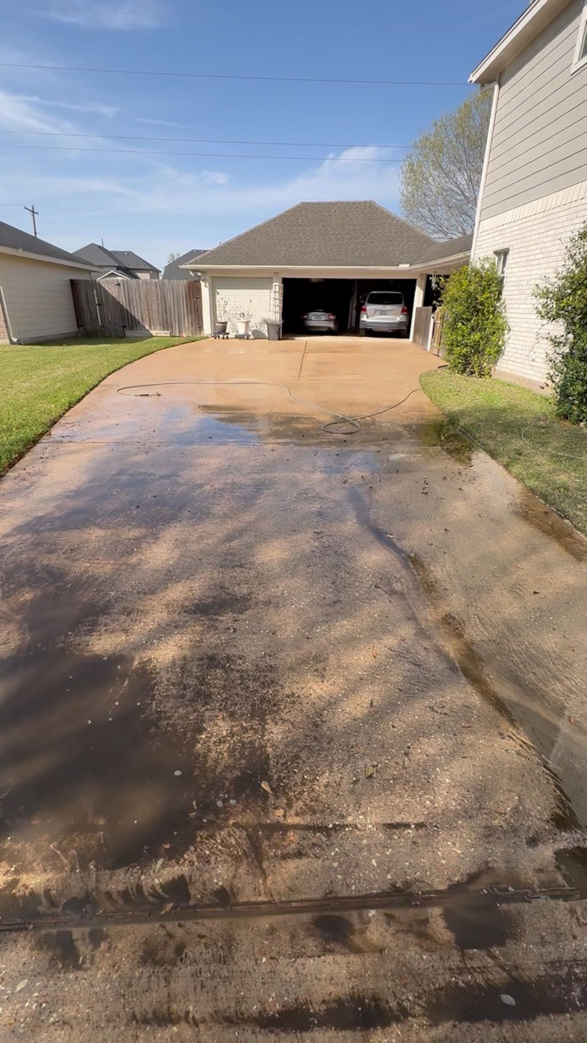 Driveway leading to an open garage between two houses on a sunny day