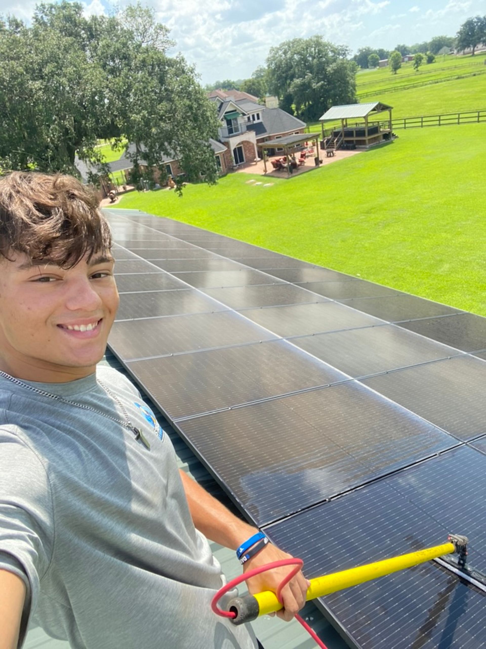 Selfie on a rooftop with a bright green lawn and trees in the background