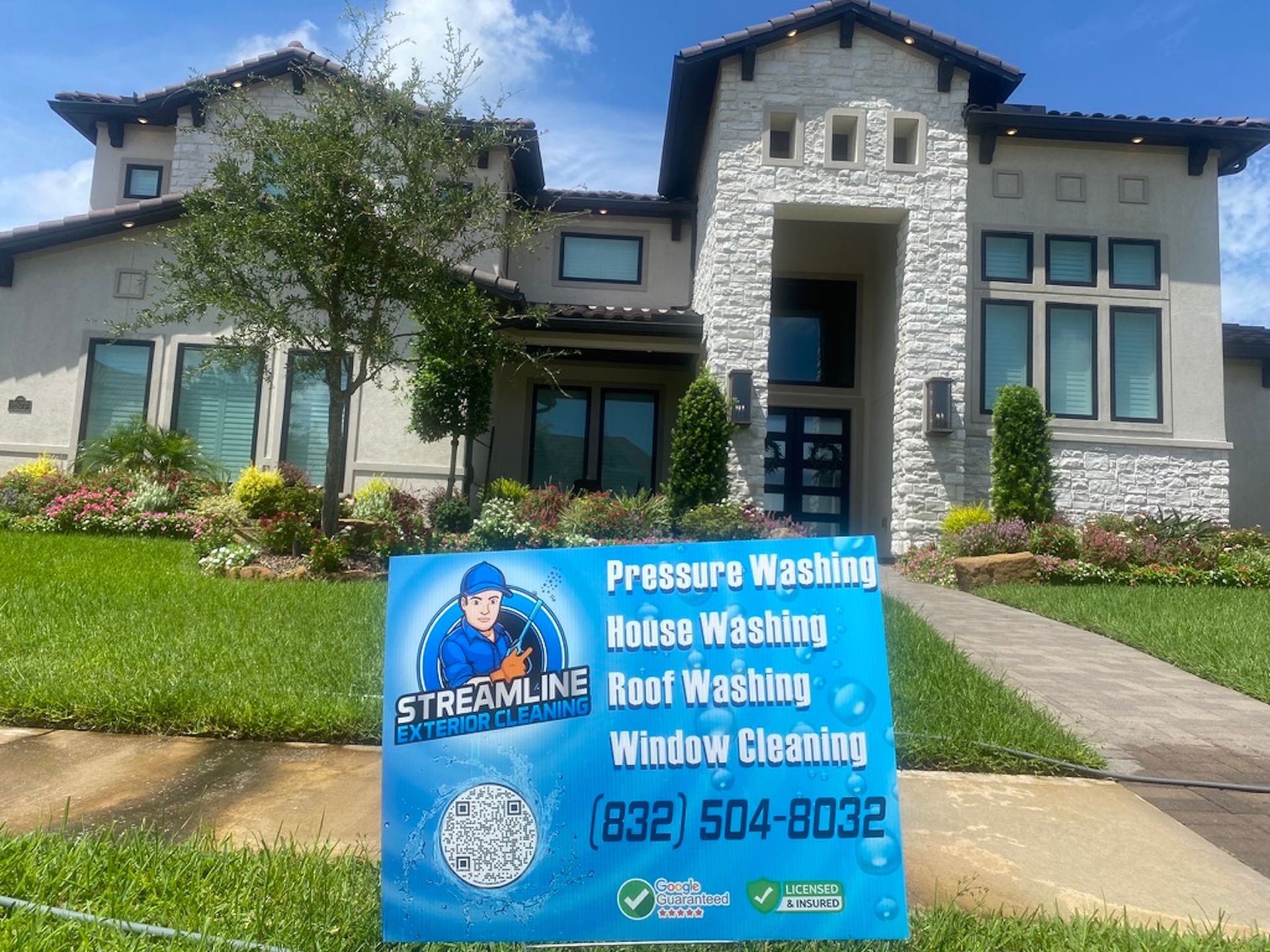 Blue lawn sign for Streamline in front of a house, listing pressure washing and roof cleaning services.