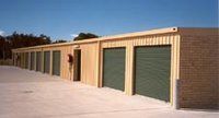 A row of storage units with green doors on a sunny day.