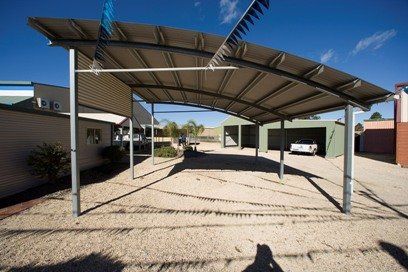 A car is parked under a canopy in a parking lot.