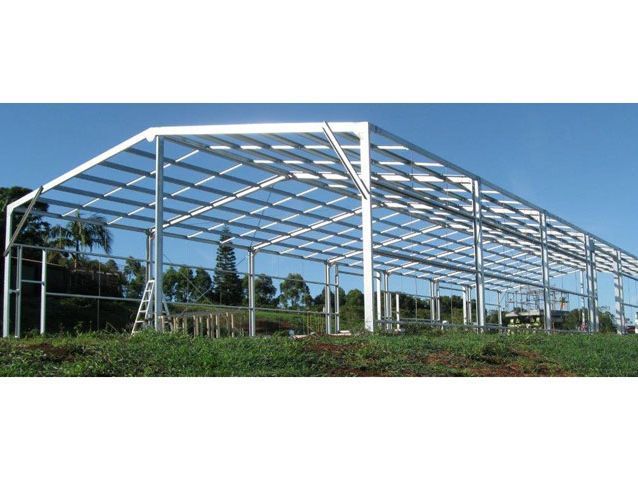 A large metal structure is being built in a grass field.