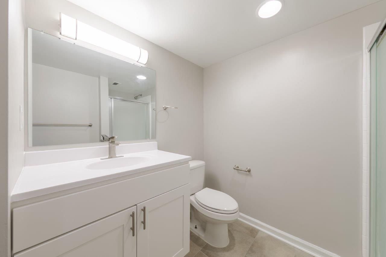 Modern white bathroom with vanity, mirror, sink, and toilet