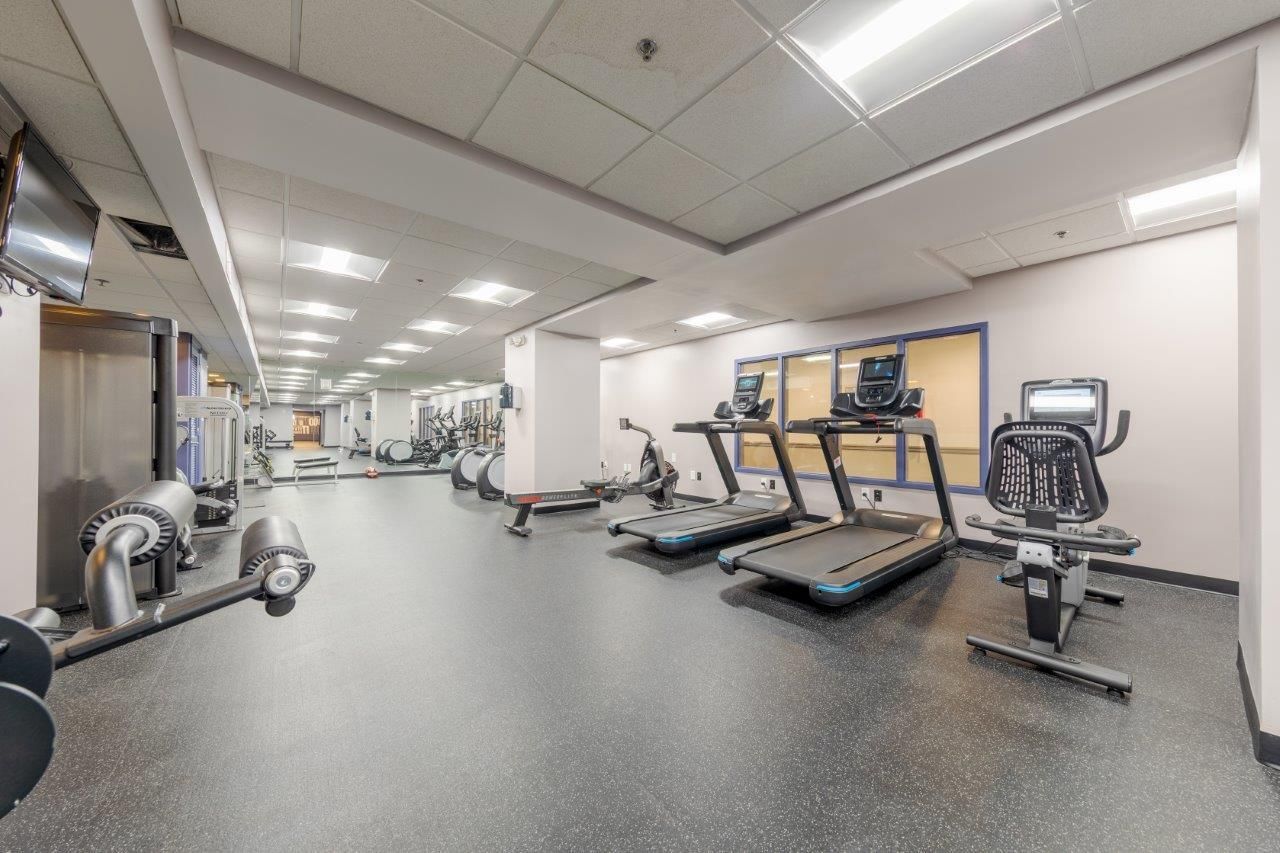 Modern gym room with treadmills, exercise bikes, and weight equipment under bright overhead lights