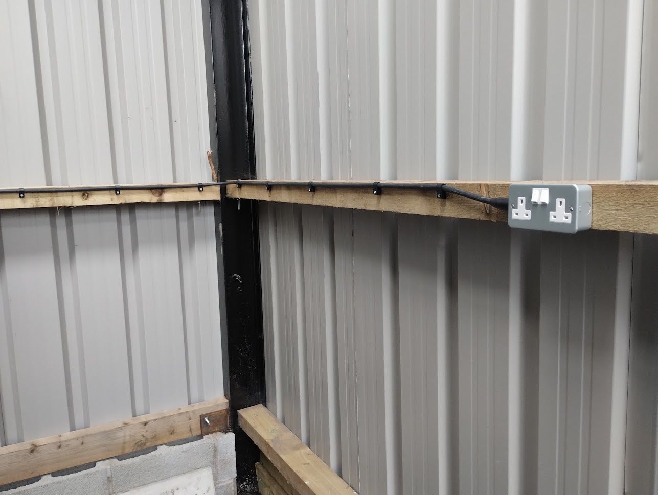 Armoured cable clipped to wooden joists with metal clad socket