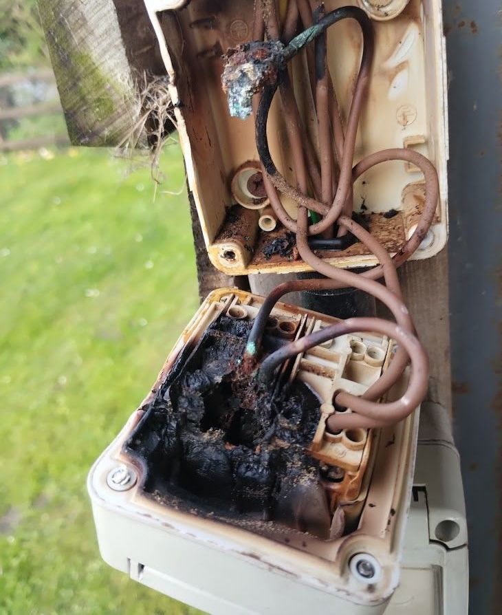 Photograph of an outdoor socket which has overheated and become seriously damaged due to the loose termination of cables