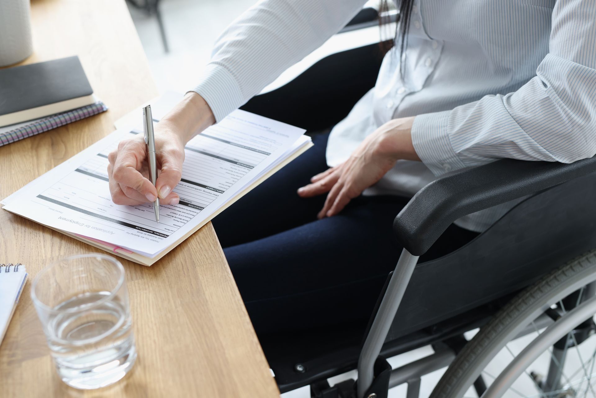 Disabled woman in wheelchair filling out application.