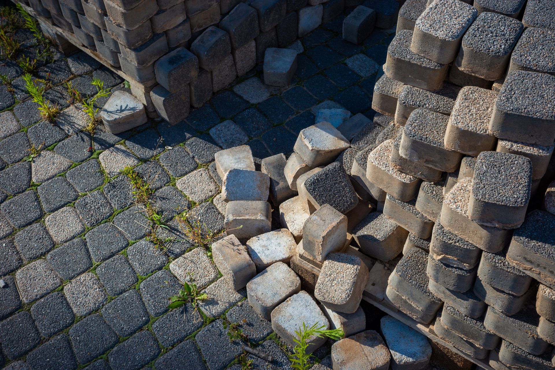 Stacked concrete pavers with a small pile of loose gray stones on a paved surface