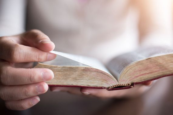 Hands turning the page of an open, old book.