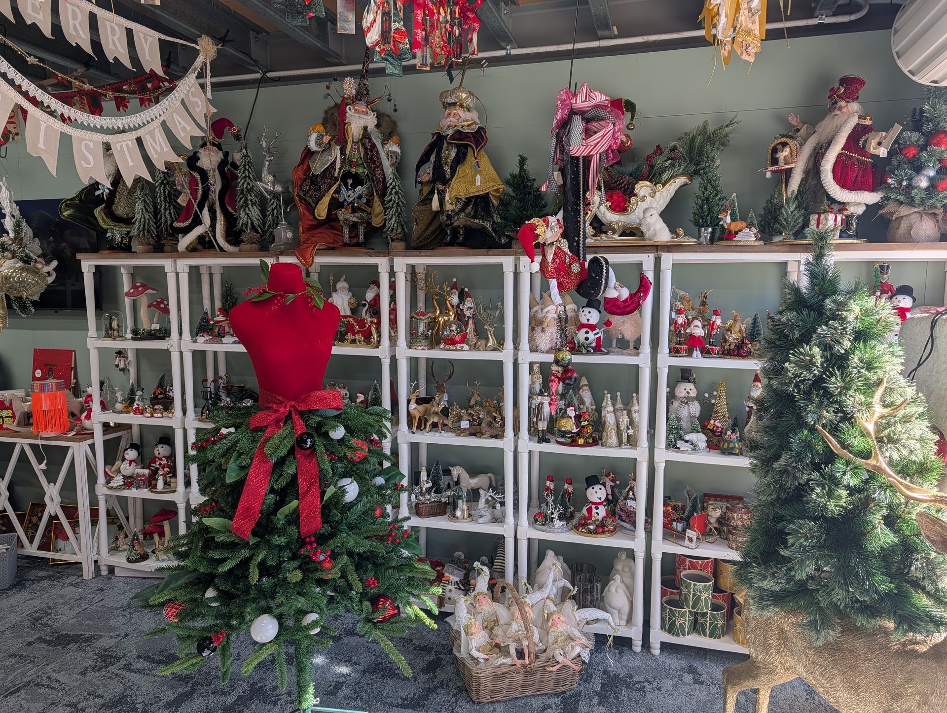 Christmas market stall with shelves of figurines, green garlands, and two decorated trees