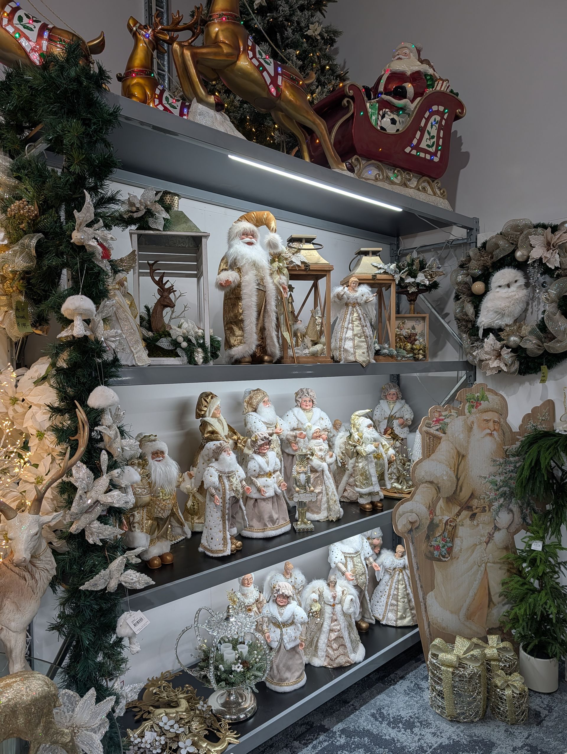 Shelves of white and gold religious figurines and floral arrangements in a decorative display