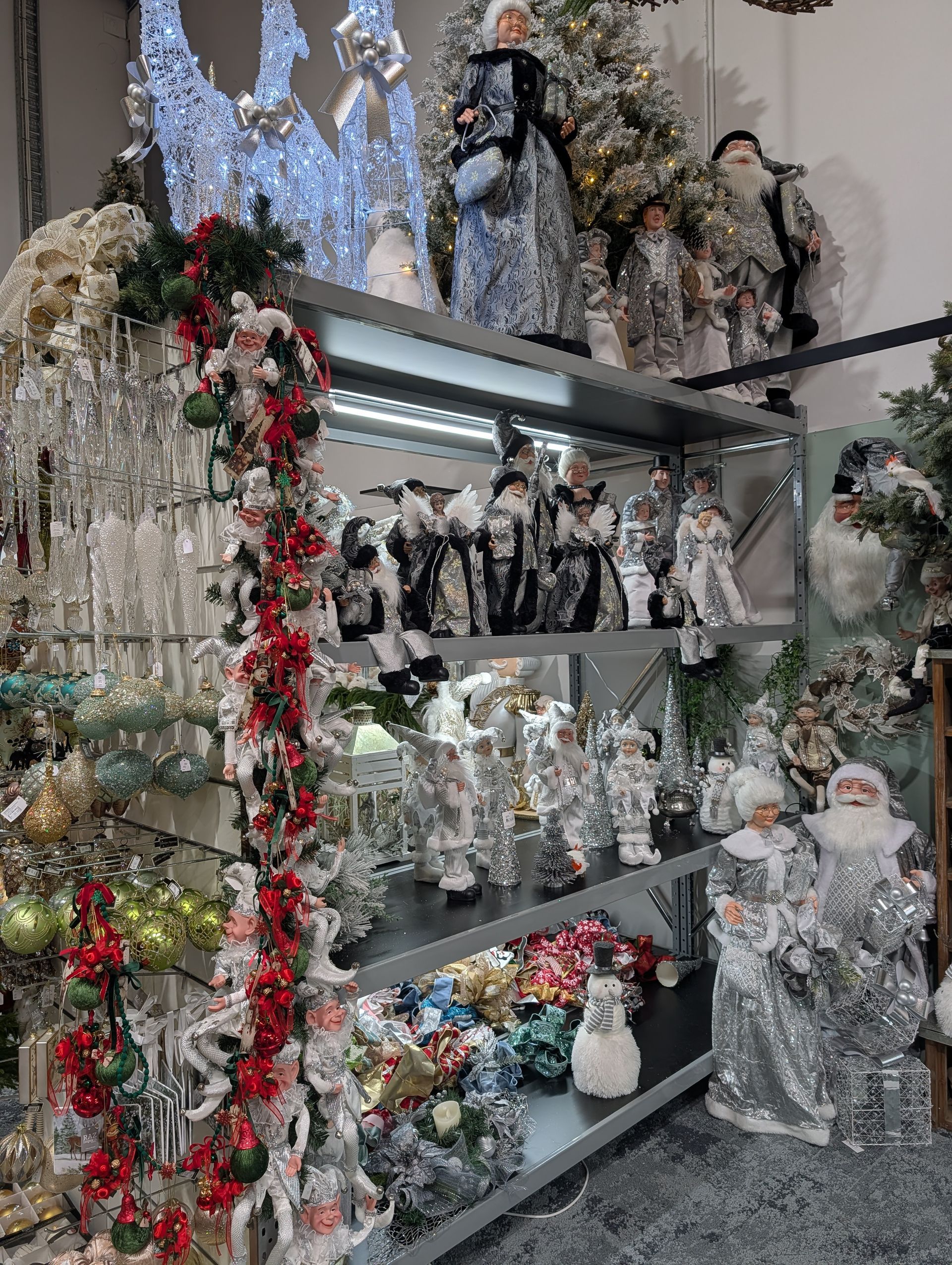 Christmas figurines and ornaments displayed on shelves, with silver, red, and white decorations
