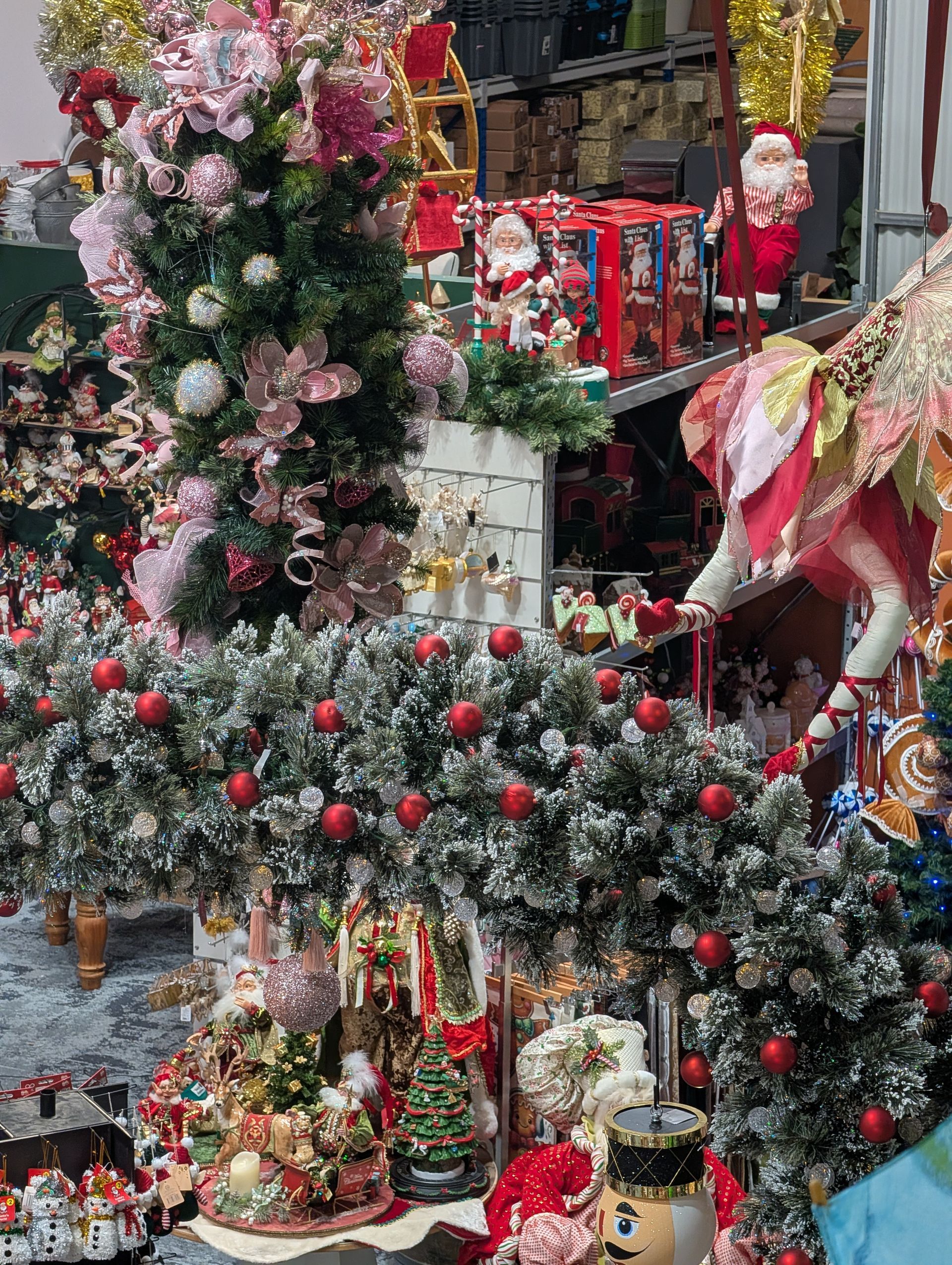 Festive Christmas display with wreaths, garlands, red ornaments, and Santa figures in a shop window