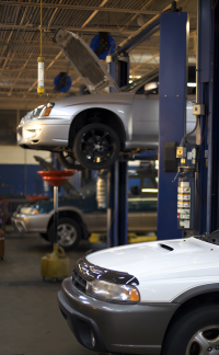 A Car on a Lift in a Garage With the Hood Open — Vanderpoel Smash Repairs in Tuggerah, NSW