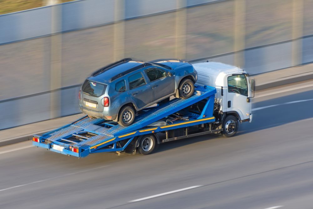 A Tow Truck is Carrying a Car on the Back of It — Vanderpoel Smash Repairs in Bateau Bay, NSW