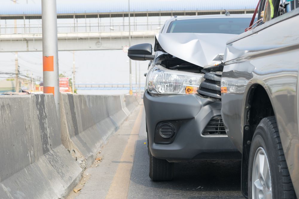 A Car With a Damaged Front End is Parked Next to a Truck on a Highway — Vanderpoel Smash Repairs in Central Coast, NSW