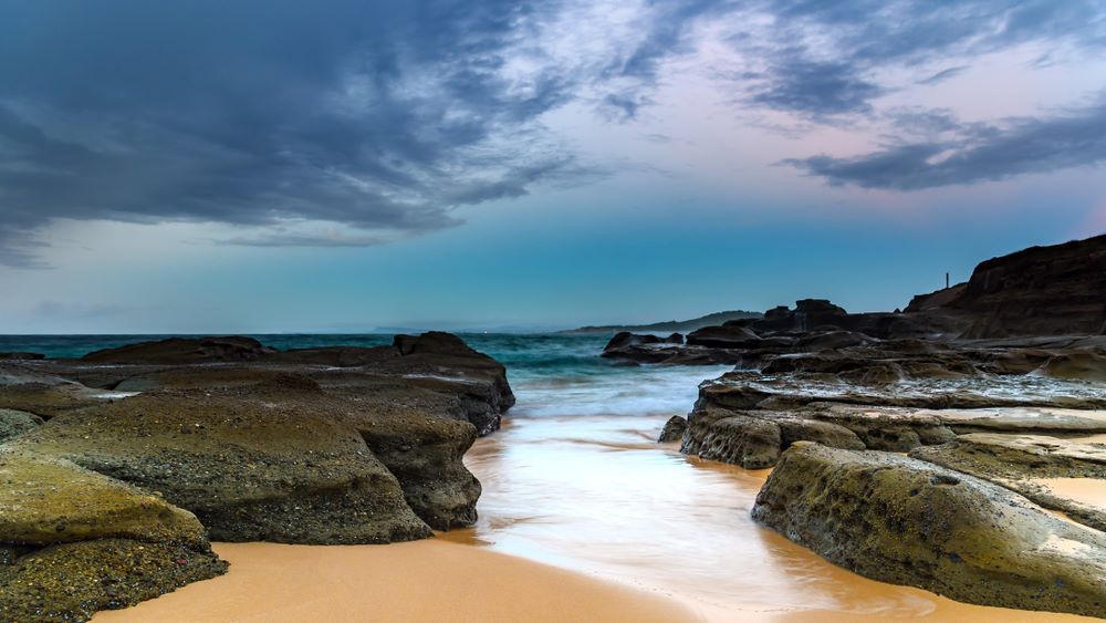 A Beach With Rocks and Waves Coming in on a Cloudy Day — Vanderpoel Smash Repairs in Wyong, NSW