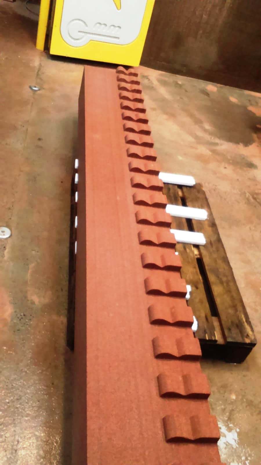 Rust-red brick wall with stepped top beside a wet floor and a yellow cabinet in the background