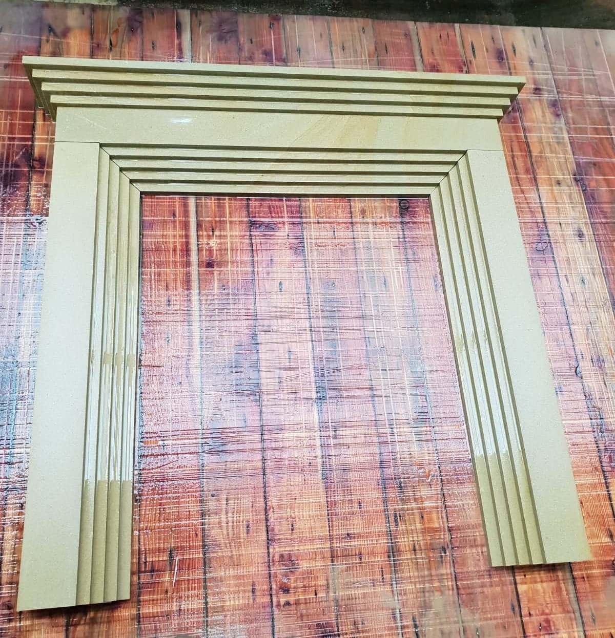 Stacked green wooden frame moldings on a wood floor.