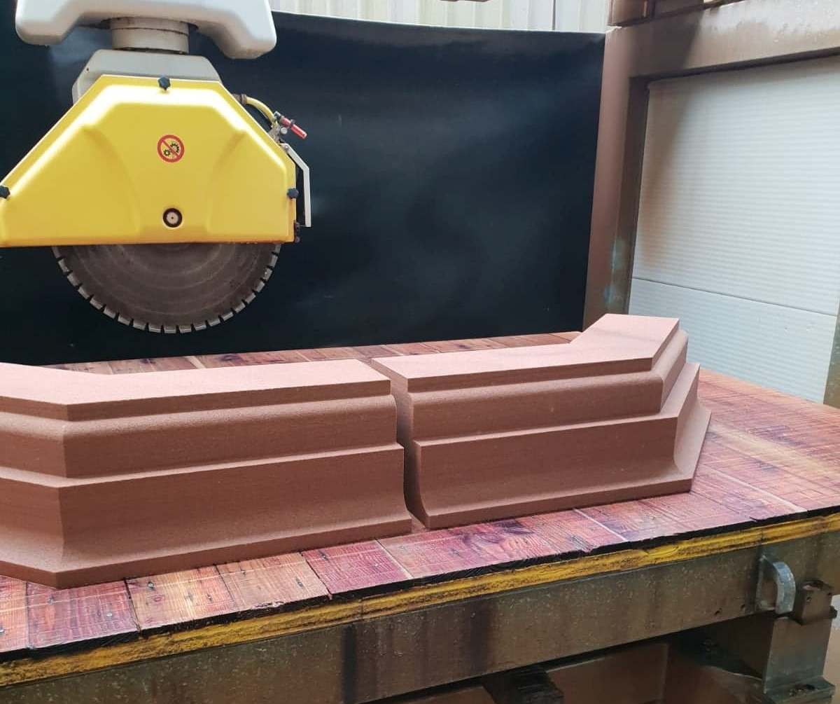 Yellow circular saw cutting stacked brown material on a workshop table