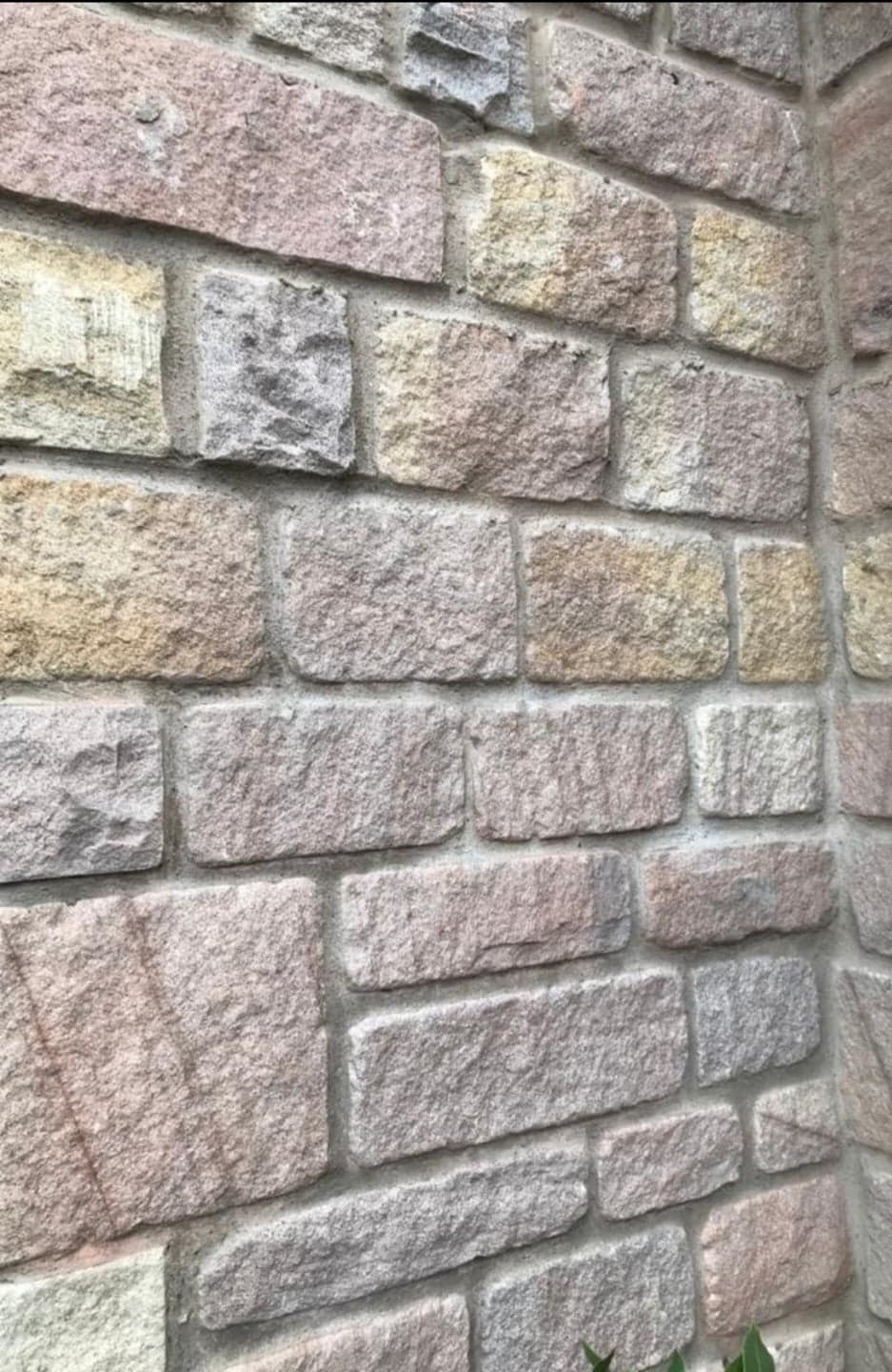 Close-up of a stone wall with rough beige, gray, and pink rectangular blocks
