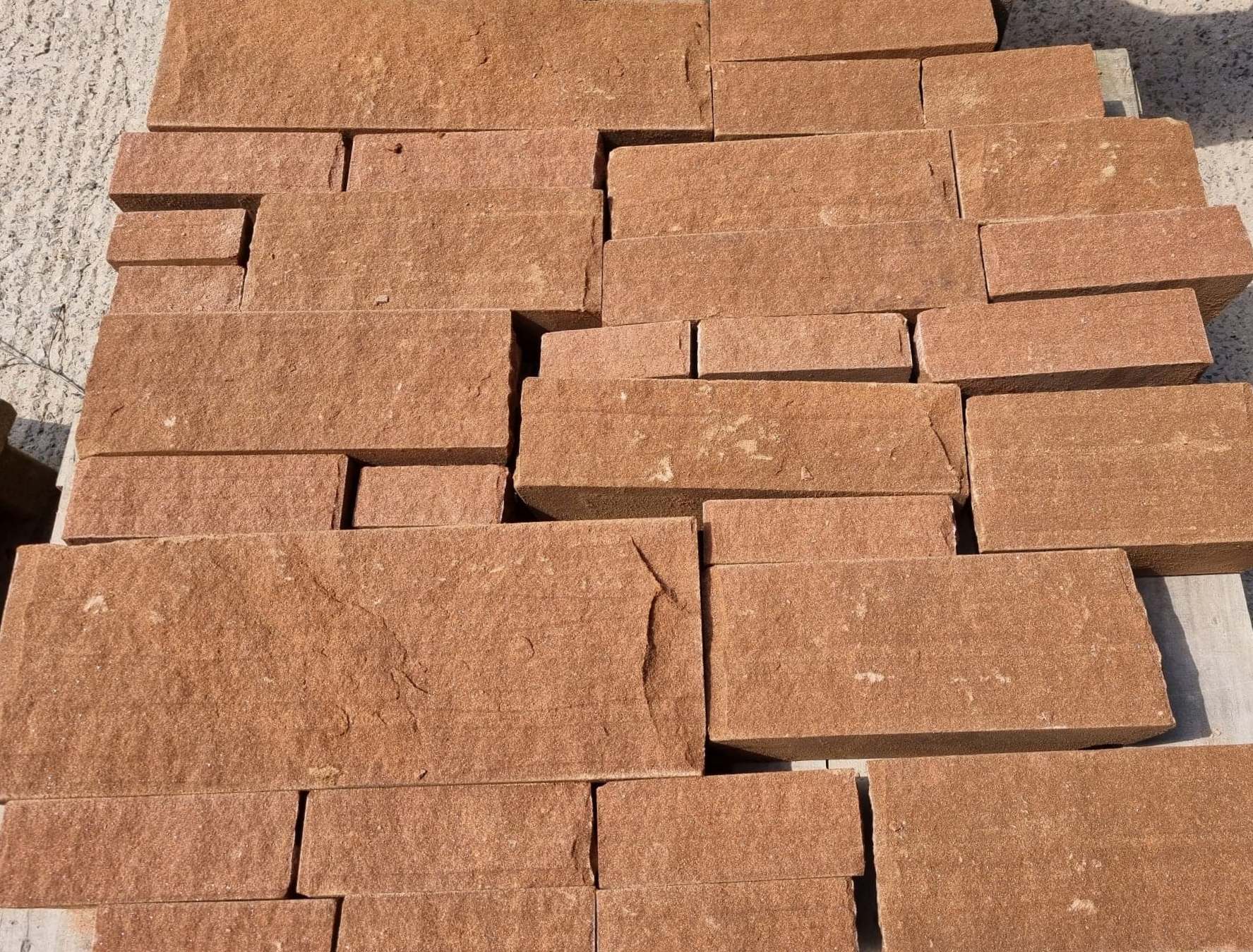 Stacked reddish-brown stone pavers laid in an overlapping pattern outdoors