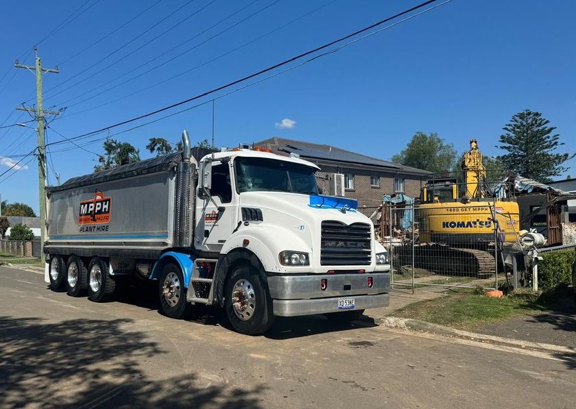 A dump truck is parked on the side of the road next to a house.